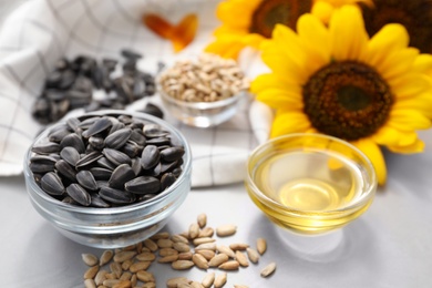 Photo of Sunflower oil and seeds on grey table, closeup