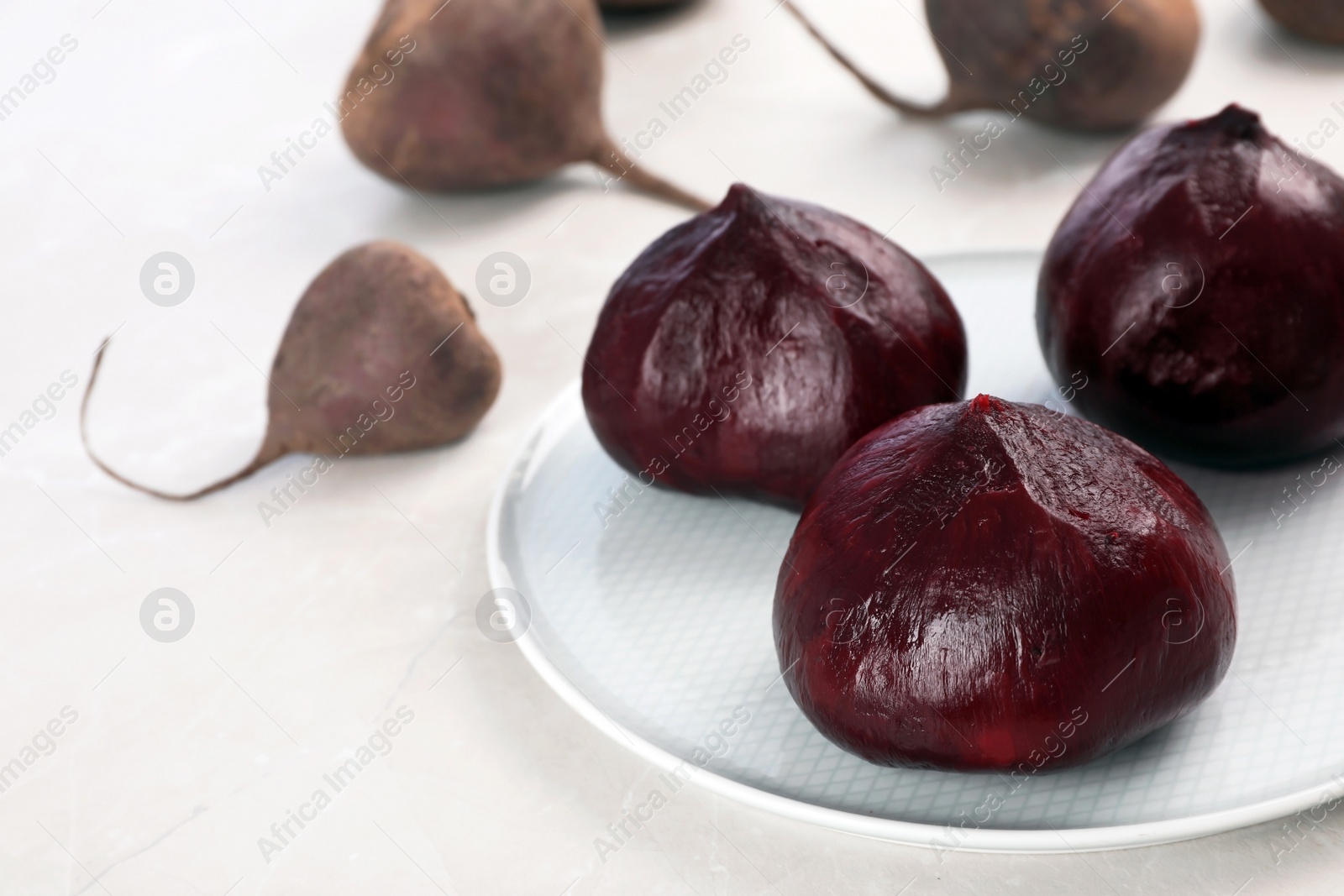 Photo of Plate with ripe peeled beets on table