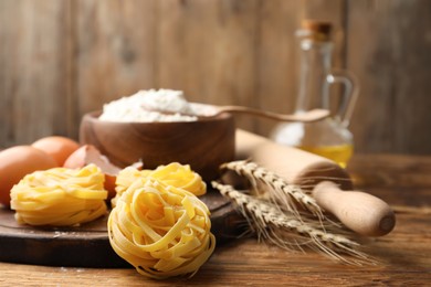 Uncooked homemade pasta and ingredients on wooden table. Space for text