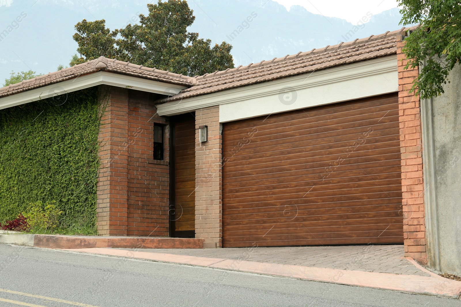 Photo of Brick building with closed wooden garage door. Exterior design