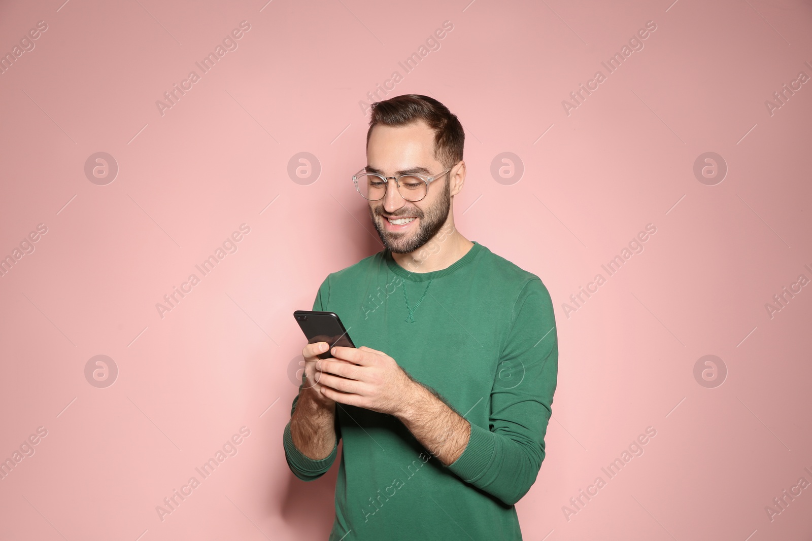 Photo of Handsome young man with mobile phone on color background