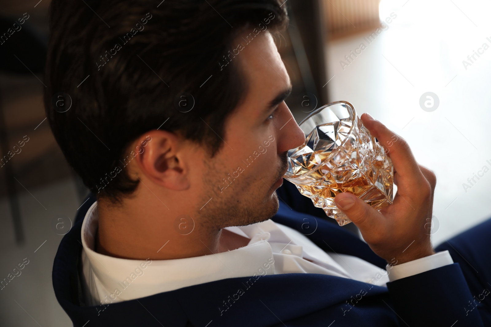 Photo of Young man with glass of whiskey indoors