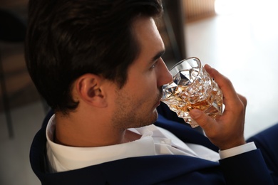 Young man with glass of whiskey indoors