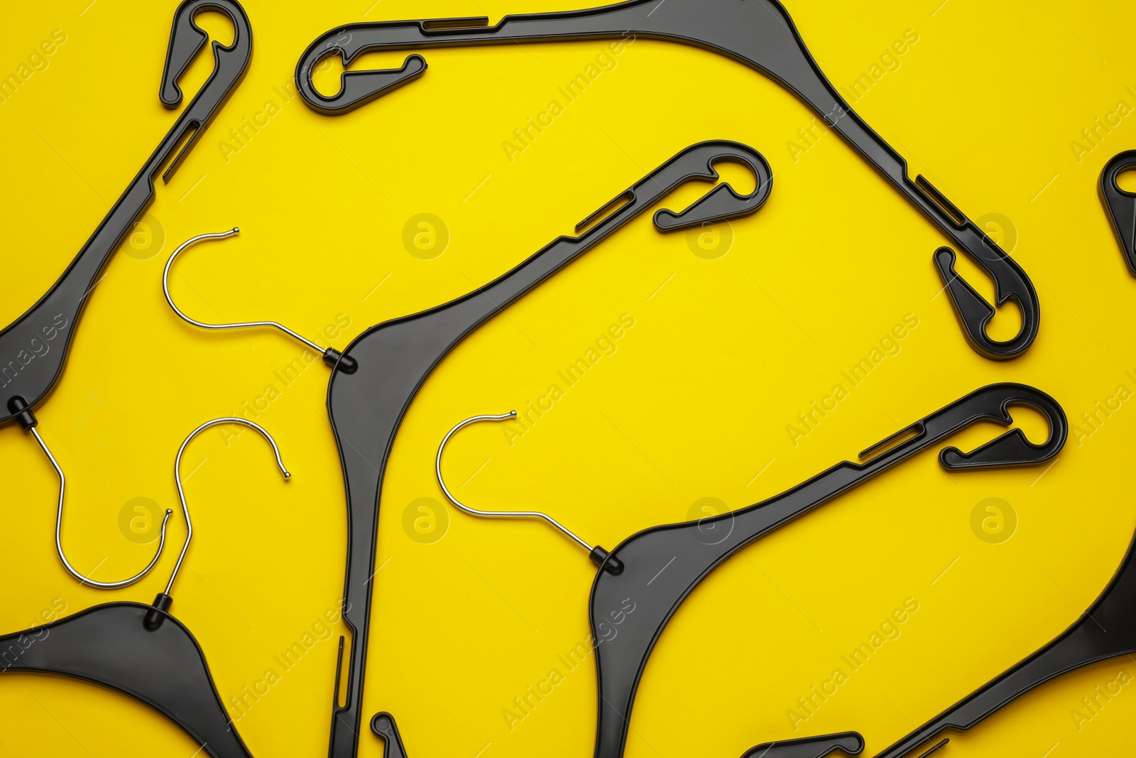 Photo of Empty hangers on yellow background, flat lay