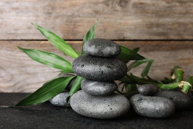 Photo of Stacked zen stones and bamboo leaves on table against wooden background