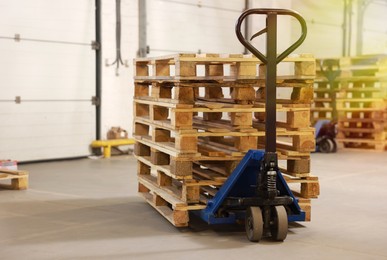 Image of Modern manual forklift with wooden pallets in warehouse