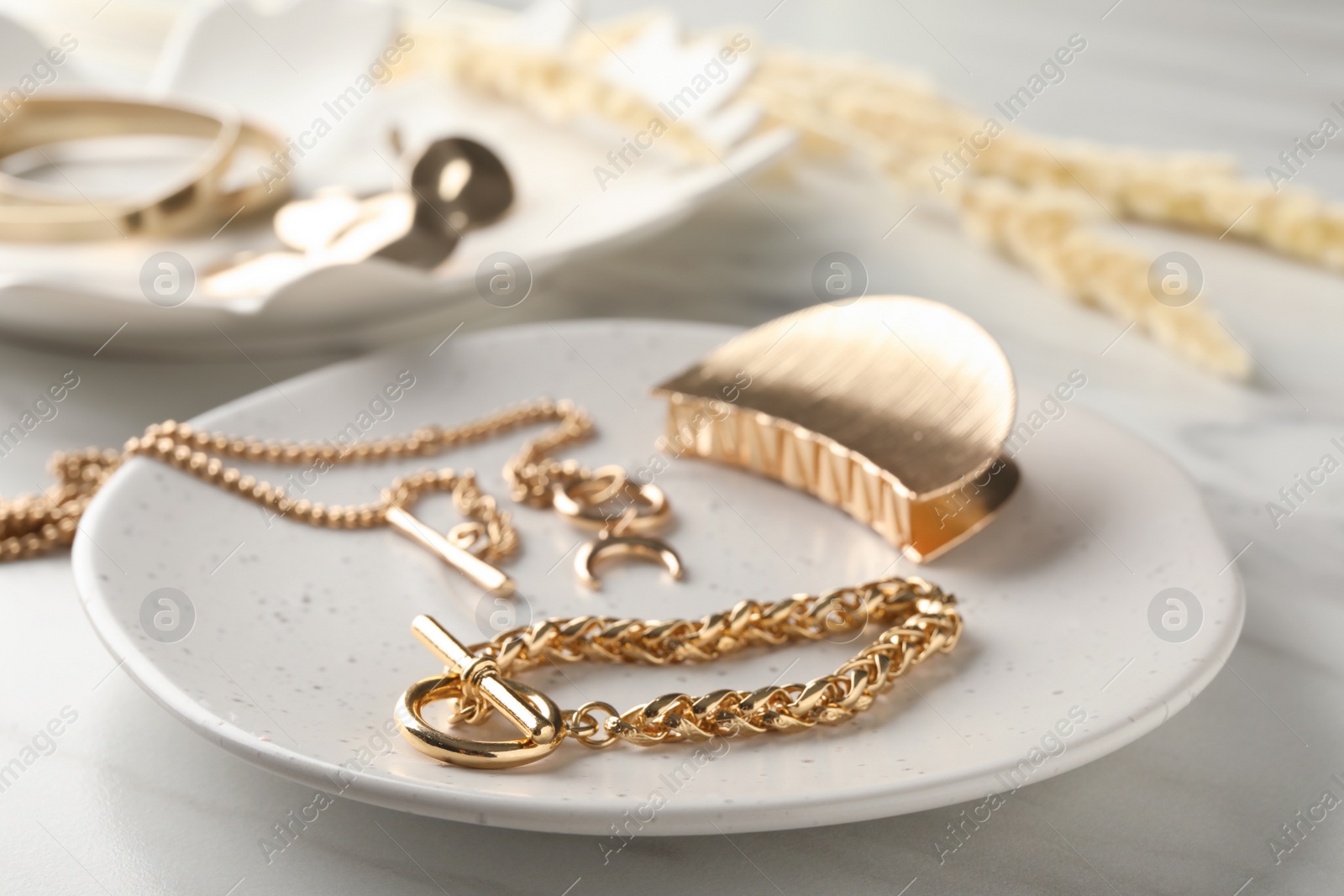 Photo of Different elegant bijouterie on white marble table, closeup