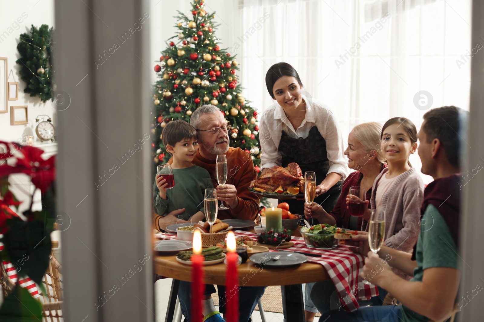 Photo of Happy family enjoying festive dinner at home, view from outside. Christmas celebration