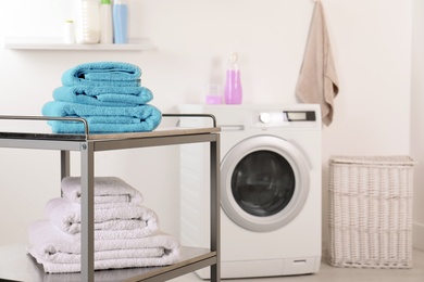 Stacked clean soft towels on table in laundry room. Space for text