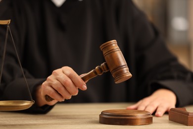 Judge striking mallet at wooden table indoors, closeup