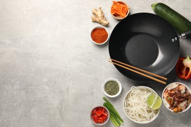 Photo of Flat lay composition with black wok, spices and products on grey textured table. Space for text
