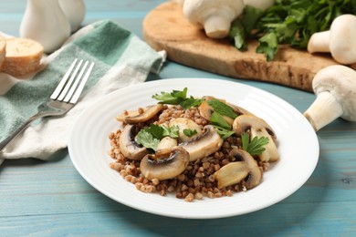 Photo of Tasty buckwheat with fresh parsley, mushrooms and fork on light blue wooden table