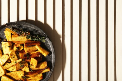 Photo of Delicious parsnips with thyme in frying pan on white wooden table, top view. Space for text