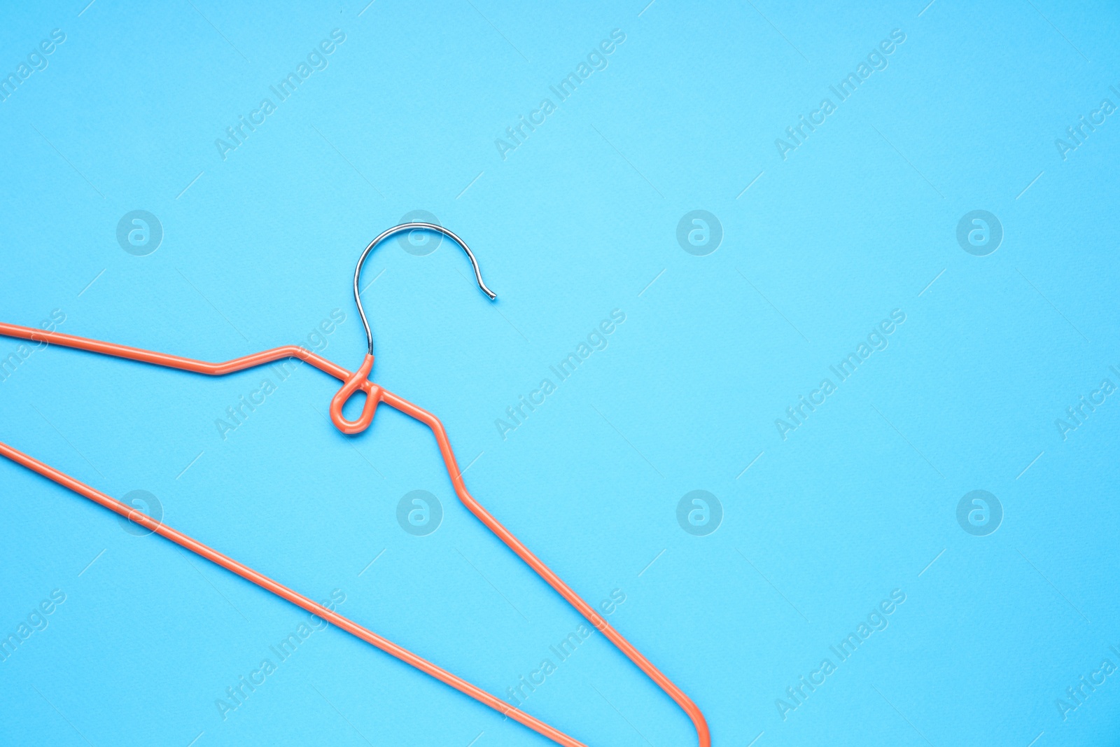 Photo of Empty orange hanger on light blue background, top view. Space for text