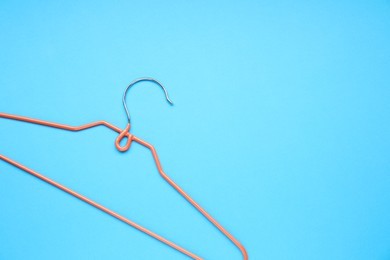 Photo of Empty orange hanger on light blue background, top view. Space for text