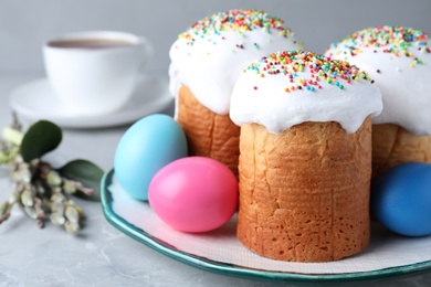 Photo of Traditional Easter cakes and painted eggs on light grey table, closeup