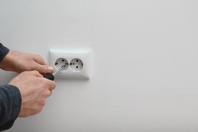 Photo of Electrician repairing wall sockets on white background, closeup. Space for text