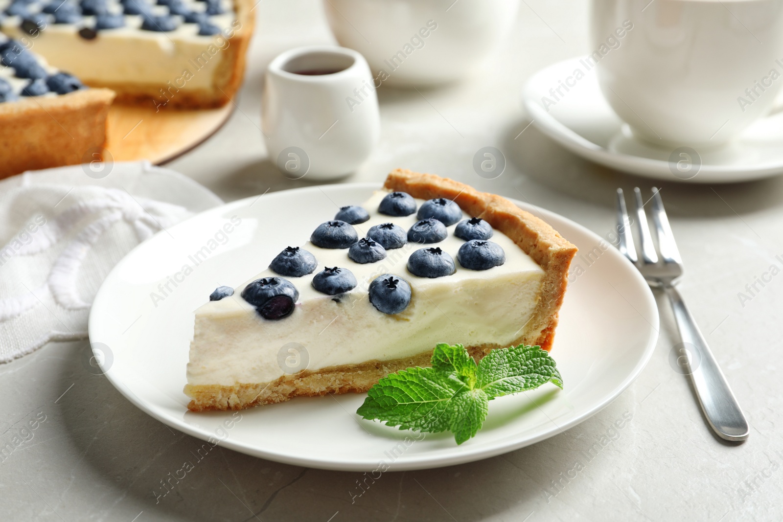 Photo of Plate with piece of tasty blueberry cake on gray table