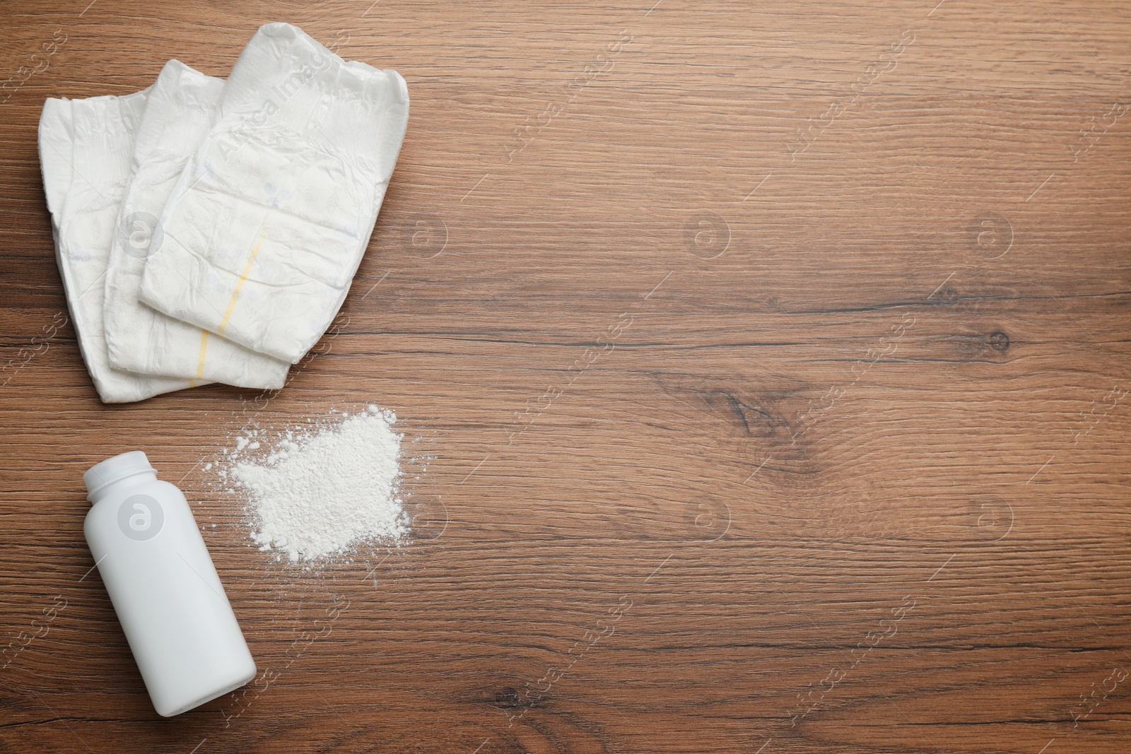 Photo of Dusting powder and diapers on wooden background, flat lay with space for text. Baby care products