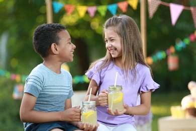 Photo of Cute little children with natural lemonade in park. Summer refreshing drink