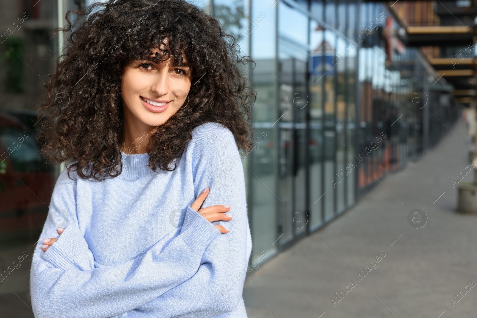 Photo of Happy young woman in stylish light blue sweater outdoors, space for text