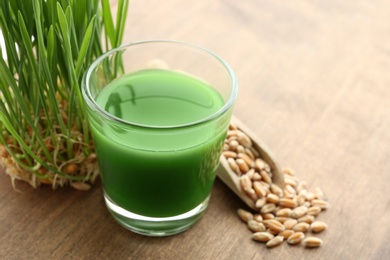 Photo of Glass of wheat grass juice, sprouts and seeds on wooden background. Space for text