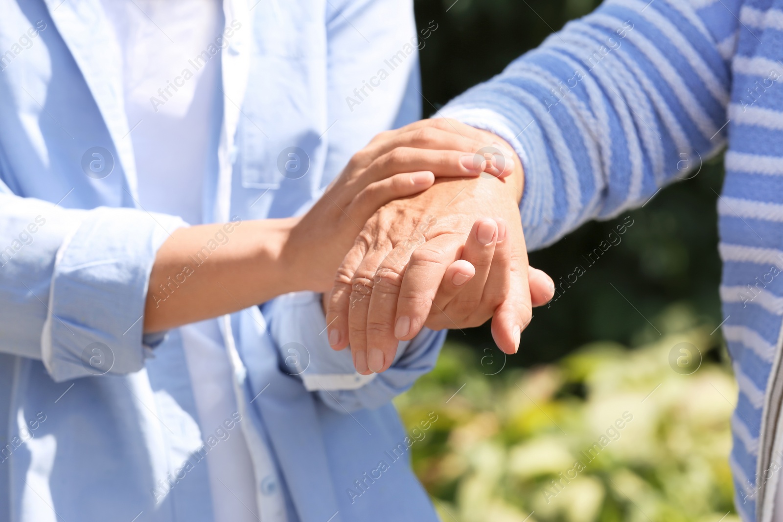 Photo of Helping hands on blurred background, closeup. Elderly care concept