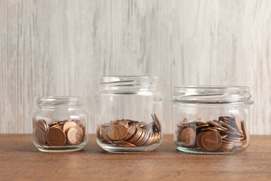 Photo of Glass jars with coins on wooden table