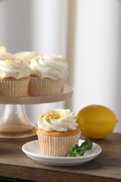 Photo of Delicious lemon cupcakes with white cream and mint on table