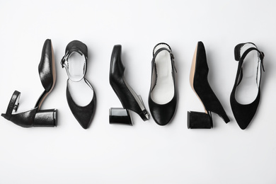 Photo of Many stylish black female shoes on white background, top view
