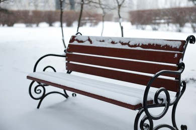 Photo of Bench covered with snow in city park
