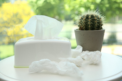 Photo of Used paper tissues, holder and cactus on white table