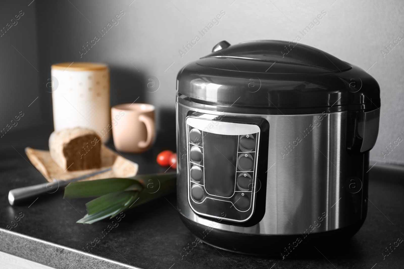 Photo of Modern multi cooker and ingredients on table in kitchen, space for text