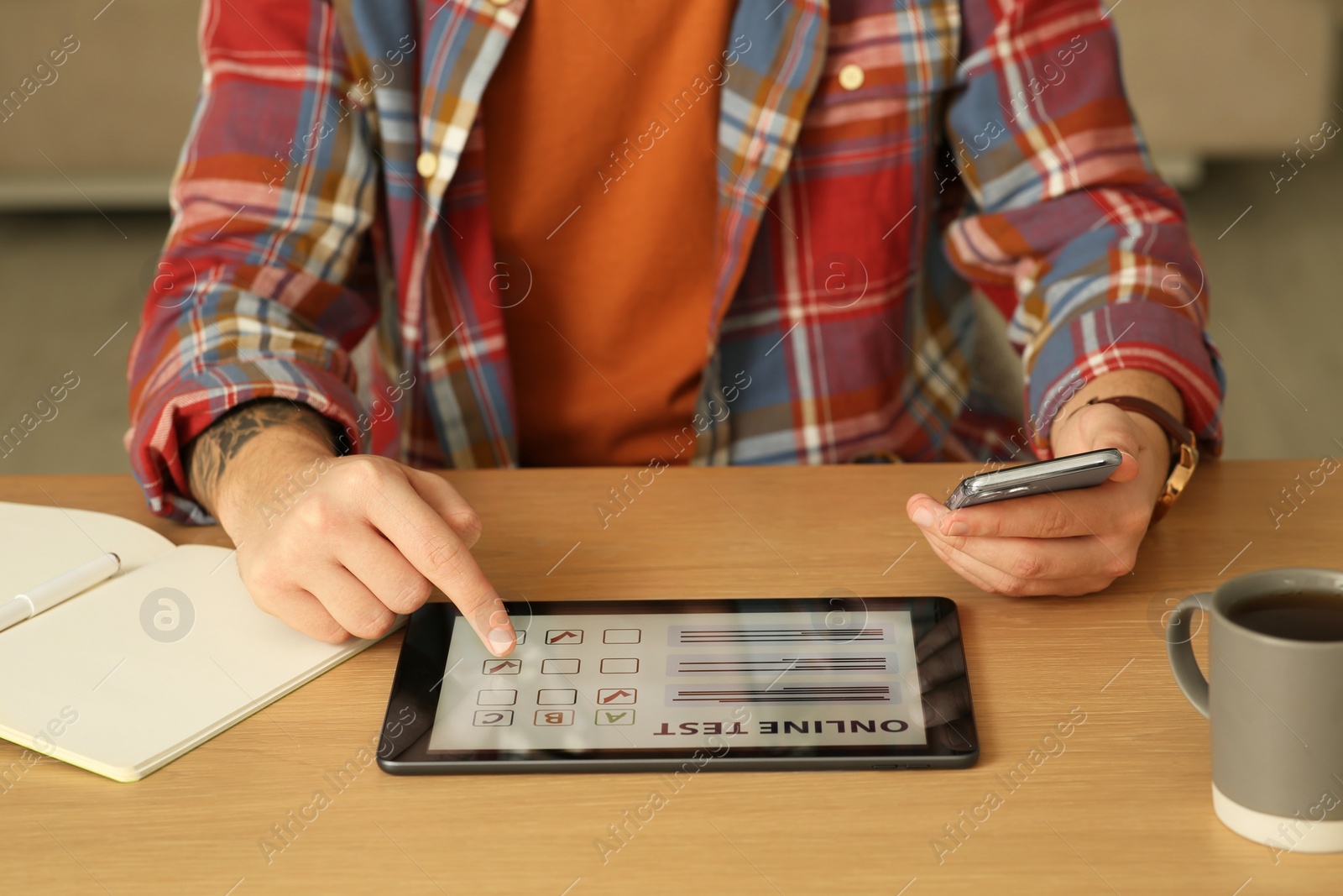 Photo of Man taking online test on tablet at desk indoors, closeup