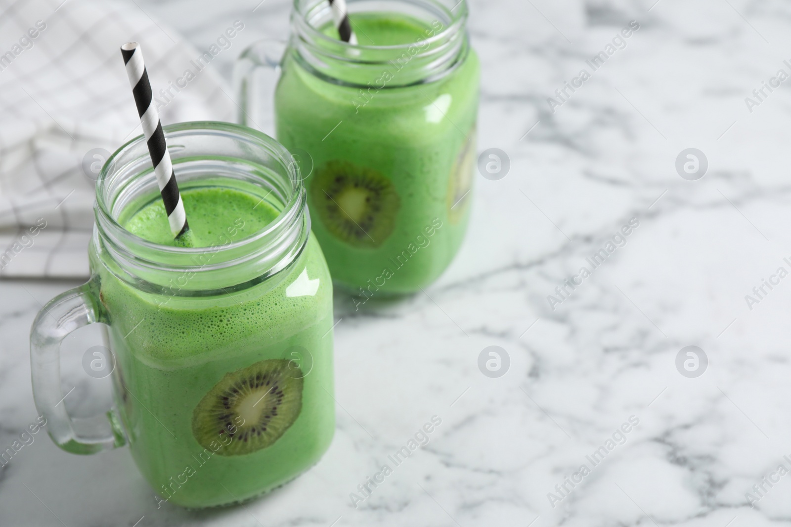 Photo of Tasty fresh kiwi smoothie on white marble table, space for text