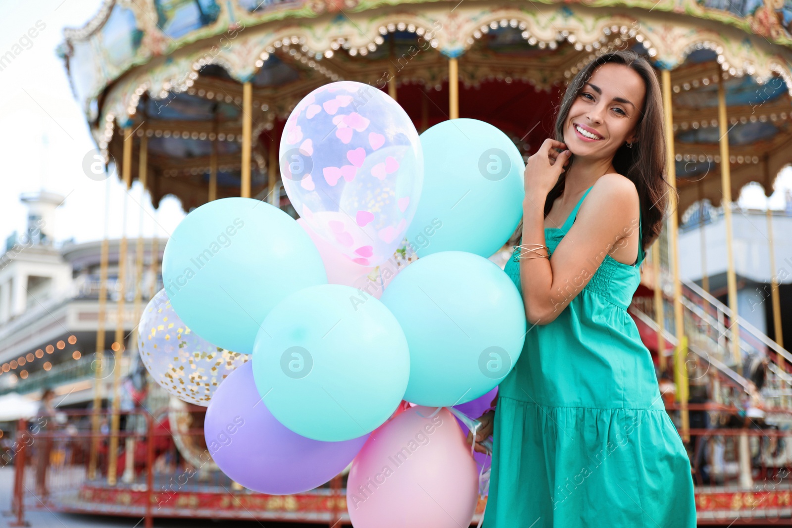 Photo of Attractive young woman with color balloons near carousel