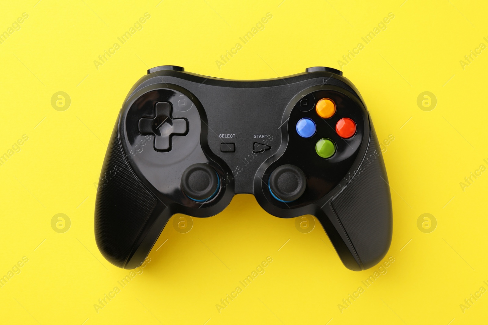 Photo of Wireless game controller on yellow background, top view