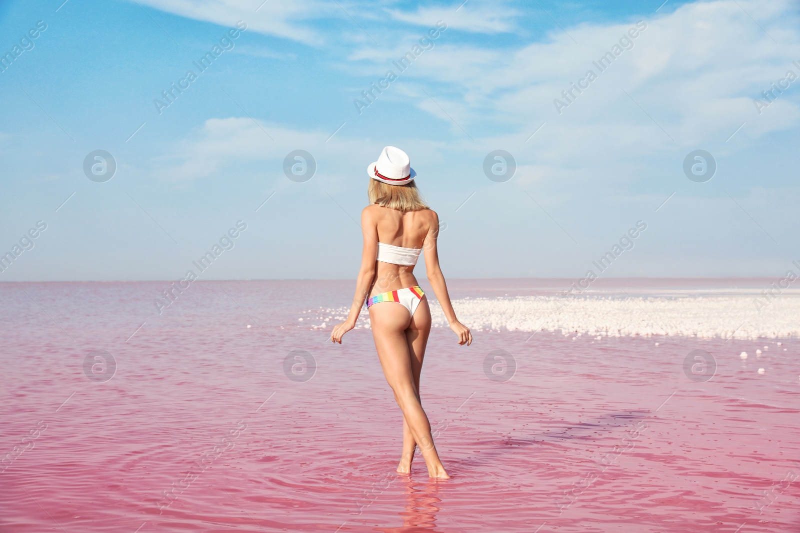 Photo of Beautiful woman posing in pink lake on sunny day