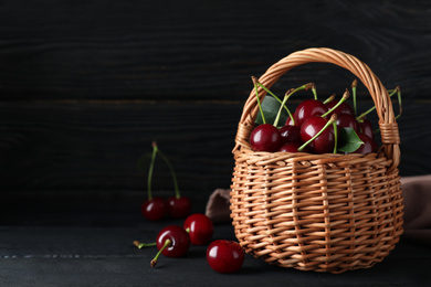 Photo of Delicious ripe sweet cherries on dark wooden table. Space for text