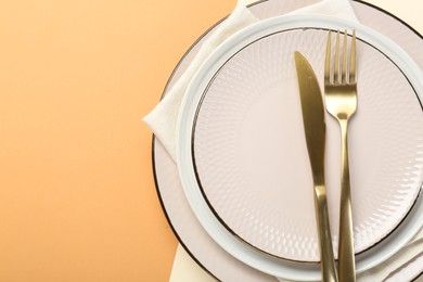 Photo of Ceramic plates, cutlery and napkin on color background, top view. Space for text