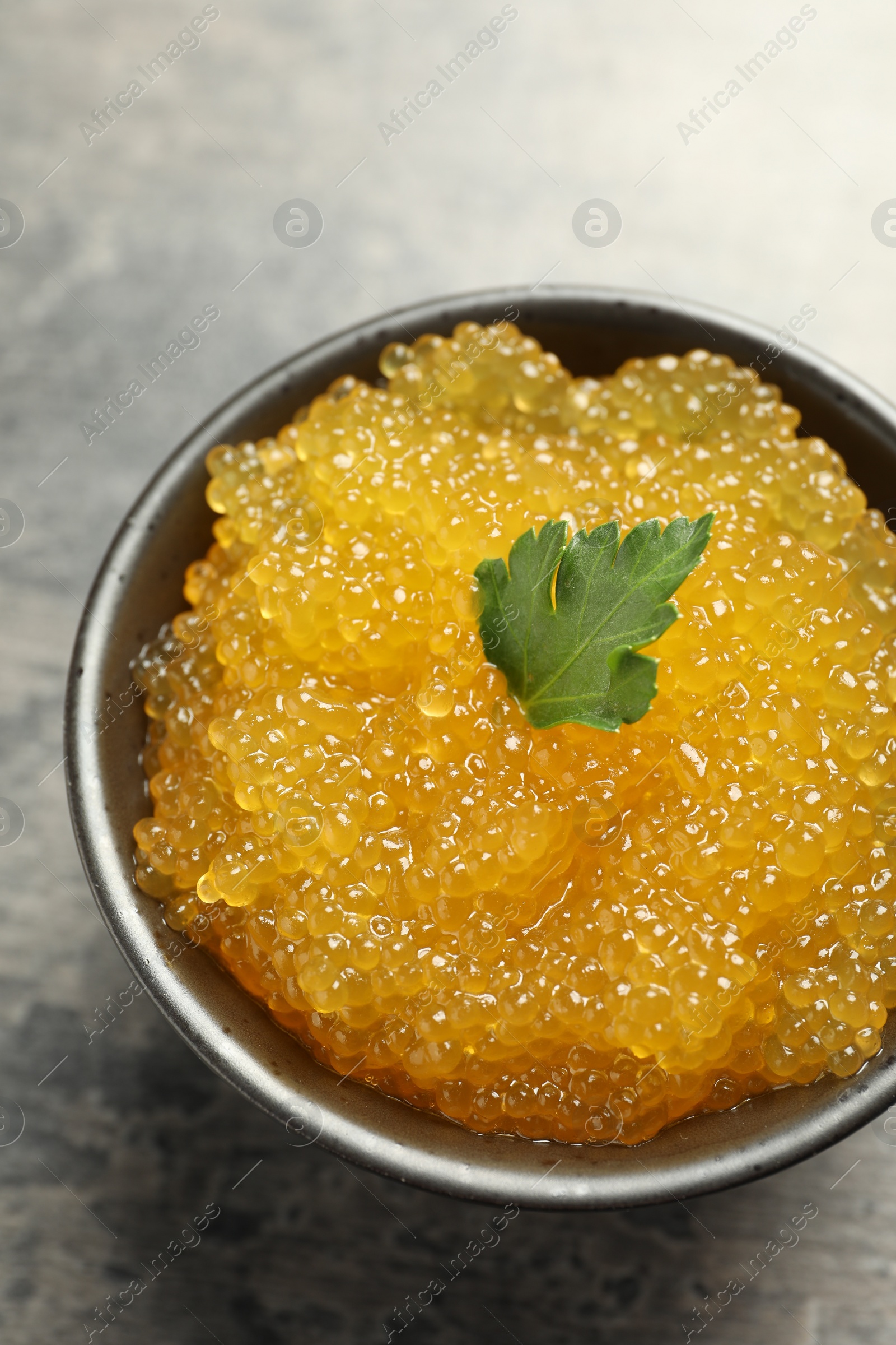 Photo of Fresh pike caviar and parsley in bowl on grey table, above view