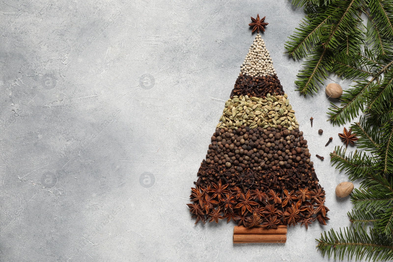 Photo of Christmas tree made of different spices and fir branches on gray textured table, flat lay. Space for text