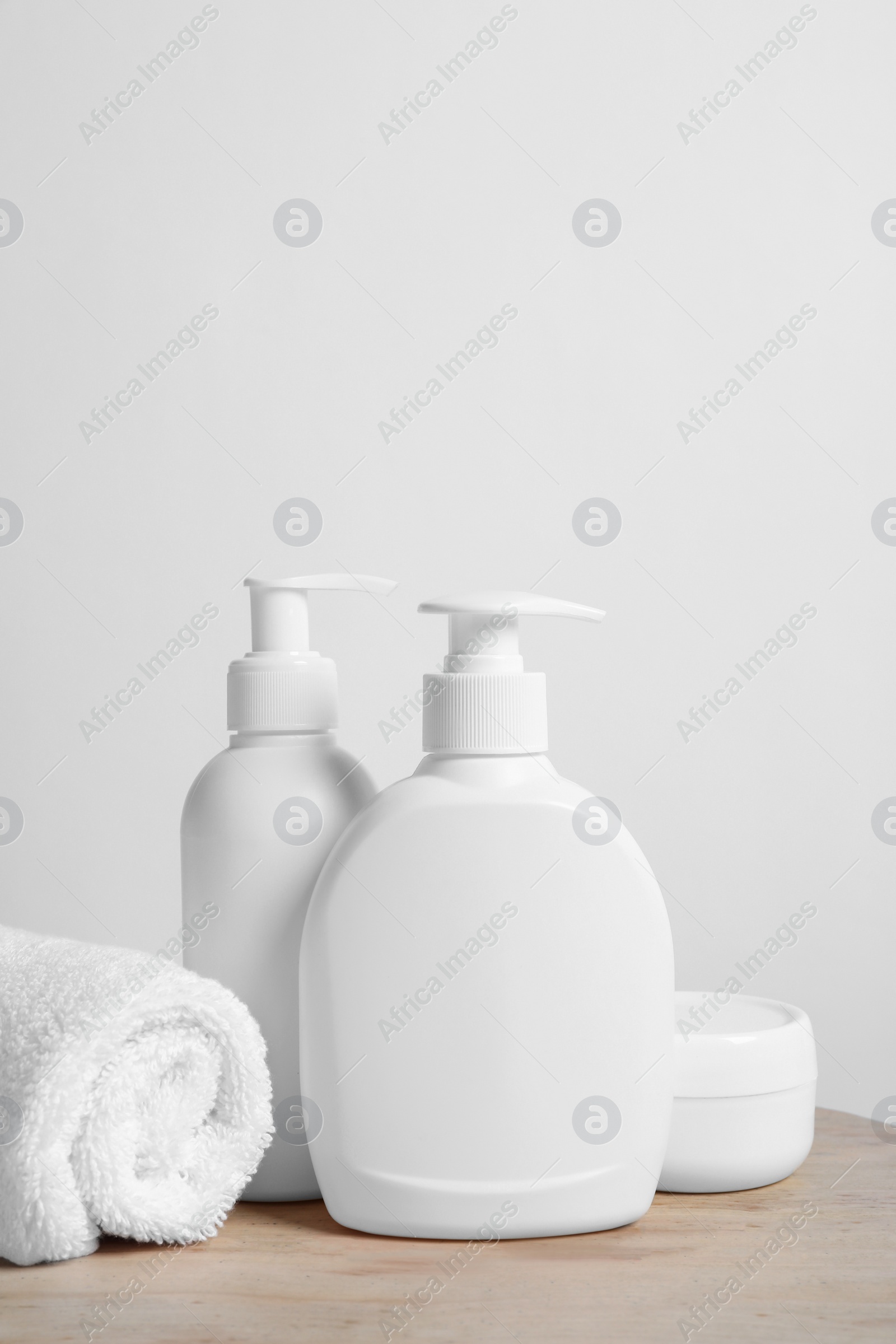 Photo of Different cosmetic products and towel on wooden tray