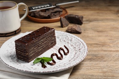 Photo of Tasty Spartak cake and mint on wooden table, space for text