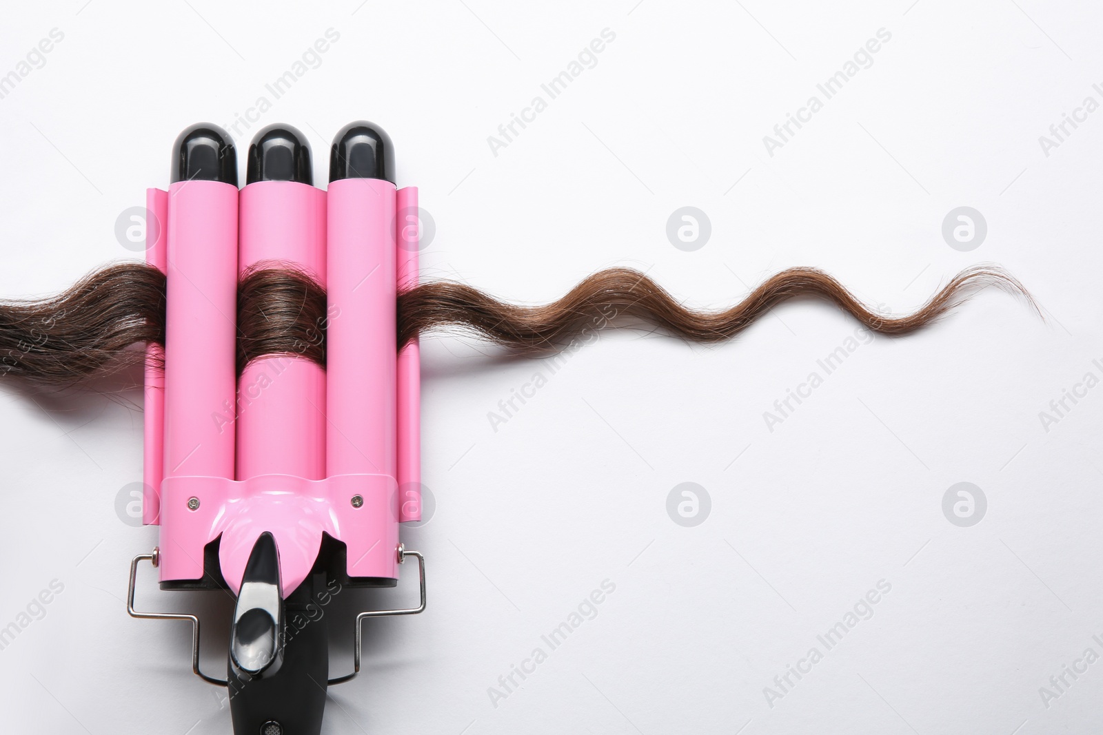 Photo of Modern triple curling iron with brown hair lock on white background, top view