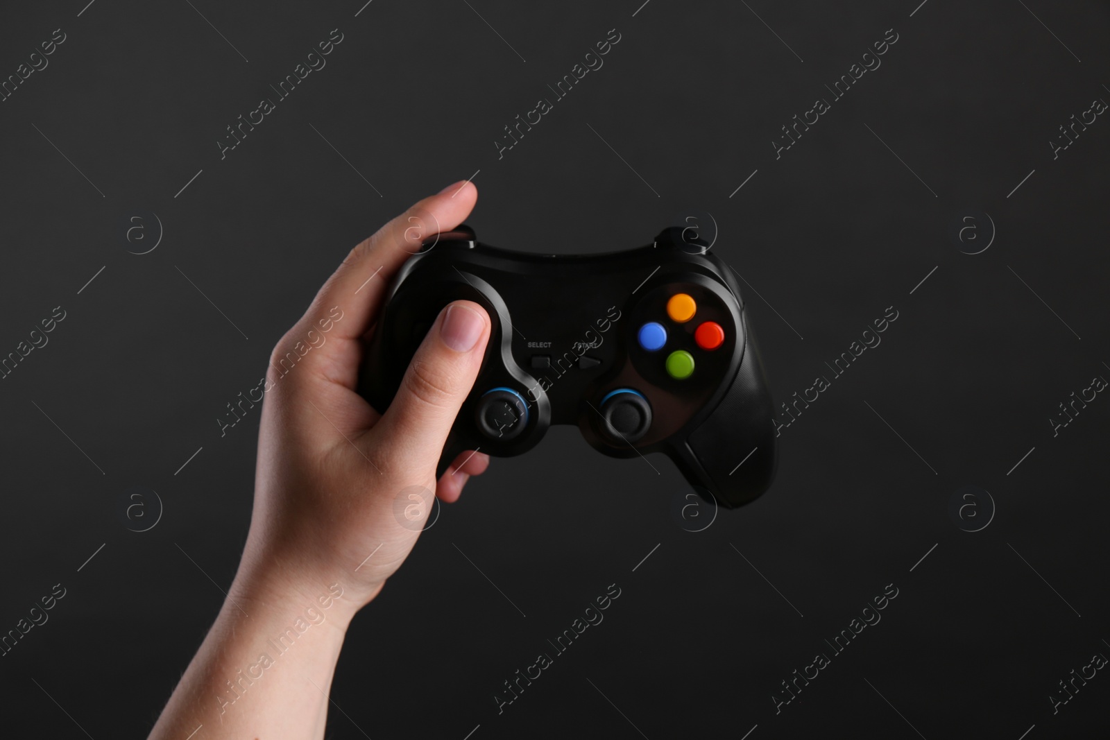 Photo of Woman using wireless game controller on dark background, closeup