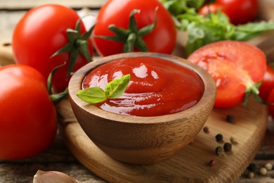 Photo of Tasty ketchup, fresh tomatoes, basil and spices on wooden table, closeup