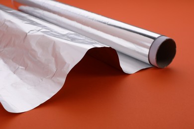 Photo of Roll of aluminum foil on orange background, closeup