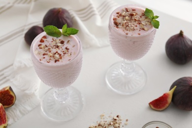 Photo of Delicious fig smoothies in glasses on white table