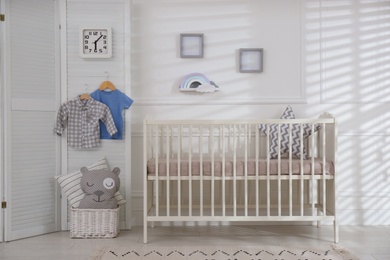 Photo of Cute baby room interior with comfortable crib and clock
